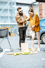 Man helping young pregnant woman feeling bad on the parking place near the supermarket