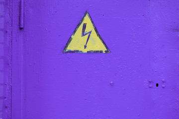 The metal surface painted by violet paint with the warning sign of danger in the form of a black...