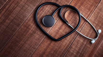 Stethoscope heart shaped on wooden background banner. Minimalistic. Heart concept, cardiology