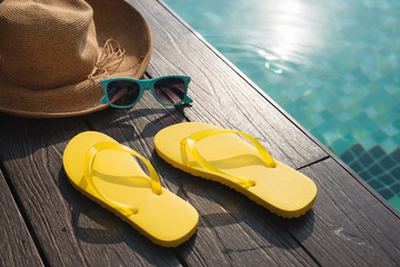 Hat, sunglasses and flip flops by swimming pool