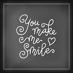 Modern calligraphy lettering of You make me smile with heart in white on chalkboard background