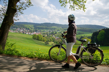 Naturerlebnis mit Elektro Fahrrad, Frau genießt Ausblick auf Frühlingslandschaft