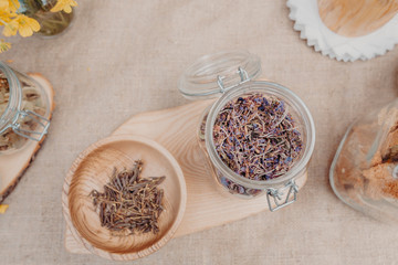 Adam's rhododendron or sagan daylya in wooden bowl with red clever in glass jar near on the table. Horizontal orientation. Top view. Copy space. 