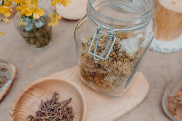 Lady’s mantle grass in glass jar and Sagan daylya in wooden bowl on the table. Grey background. Horizontal orientation. 