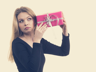 Girl holding present shaking pink gift box