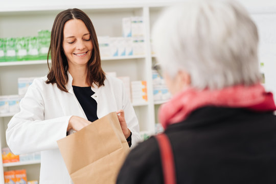 Smiling pharmacist placing medicine in a bag