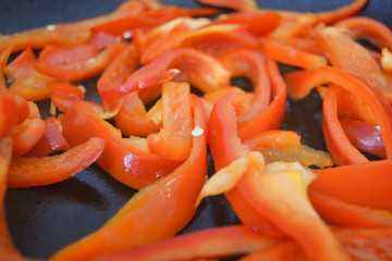 sliced roasted peppers in a pan, cooking