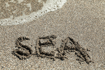 Sea sand with inscription sea, top view. Summer backdrop