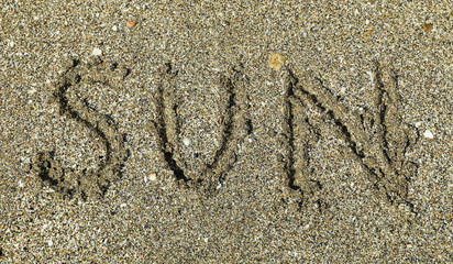 Fototapeta na wymiar Sea sand with inscription sun, top view. Summer backdrop