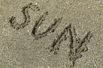 Sea sand with inscription sun, space for text. Summer backdrop