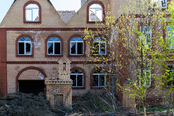 Facade of a destroyed brick building with broken Windows.