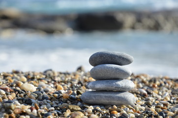 Zen pyramid of spa stones on the blurred sea background. Sand on a beach. Sea shores. Water waves texture. Place for text. concept of balance and spirituality