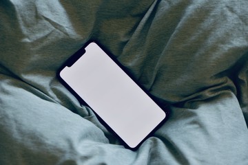 Smartphones are big part of our daily life now. New generation smartphone with blank white screen for Infographic Global Business Marketing investment Plan. The cellphone is on comfy, cozy bed.