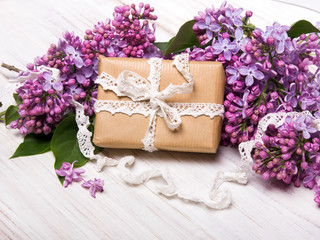 Lilac flowers, gift box on white wooden background