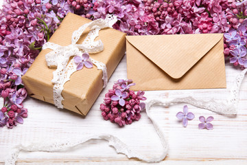 Lilac flowres, gift box and envelope on white wooden background. Retro style. Holiday composition, copy space