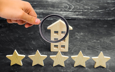 Five stars and a wooden house on a gray concrete background. The concept of the best housing,...