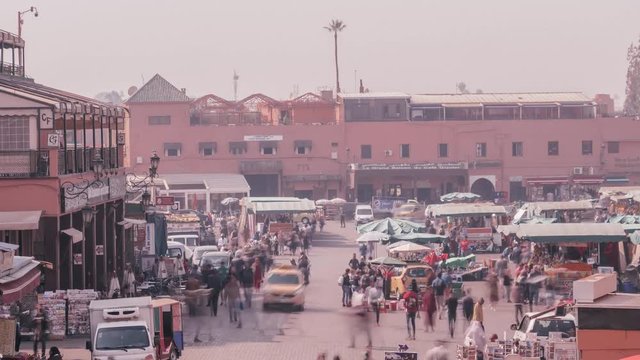 Time lapse looking above a crowded bustling street and marketplace in Marrakesh Morocco at market stalls cars people and building on a hazy afternoon