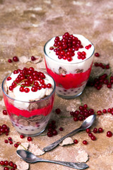 Healthy dessert with organic red currants, fresh yogurt and corn flakes. Dietary breakfast on a brown background