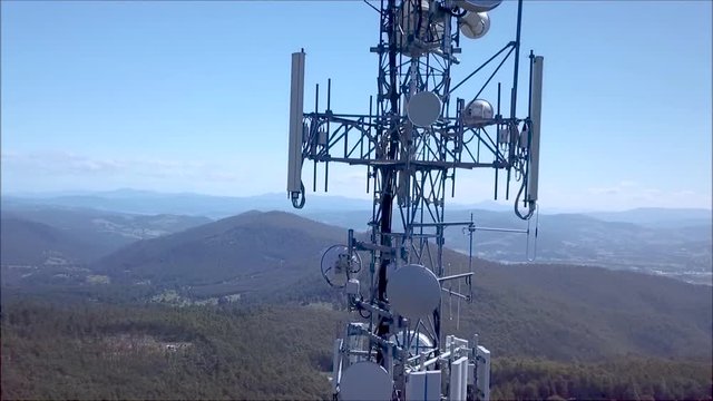AERIAL: Ascending a cell phone tower overlooking a valley
