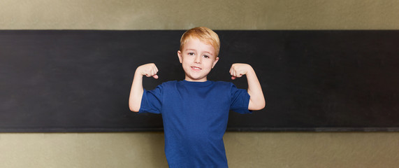 Schüler zeigt Muskeln vor Tafel in Grundschule