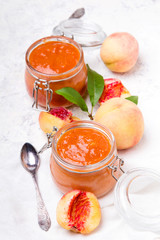 Homemade peach jam with organic fruit. Sweet preserves on a light background