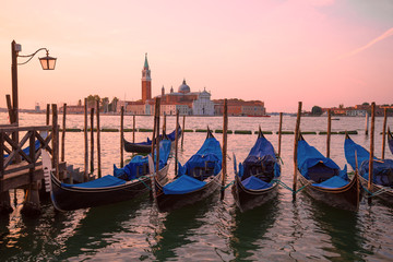 Moored gondolas on the background of the Cathedral of San Giorgio Maggiore on sunrise. Venice, Italy