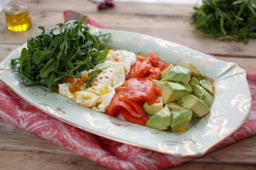 Dish with avocado, salmon, fried eggs and arugula