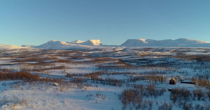 Lapporten mountains, C4k aerial, rising, drone shot, towards the lapponian mountains, near Abisko national park, at sunset, on a sunny winter evening, Kiruna, Lapland, Norrbotten, in Sweden