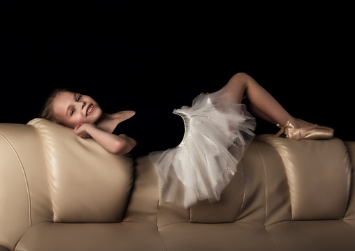 little ballerina in pointe sits and resting on the sofa. cute ballerina in the dance class is studying ballet. Classical dance, ballet