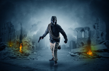 Fototapeta premium Destroyed place after a catastrophe with man in gas mask and weapon on his hand 