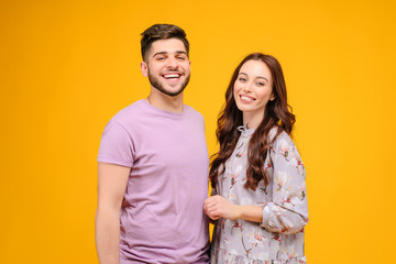 Photo of young couple man and woman smiling isolated over yellow background