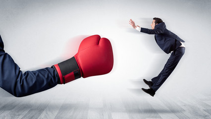 Big red boxing glove knocks out little businessman concept
