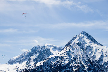 two parachutes flying in the sky over a snowed mountain