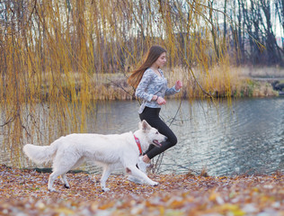 Young girl with dog running at the forest