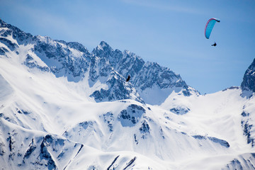 Naklejka na ściany i meble one blue parachute flying in the sky over a snowed mountain