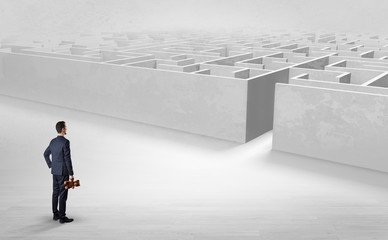 Businessman getting ready to enter the labyrinth with objects in his hand concept
