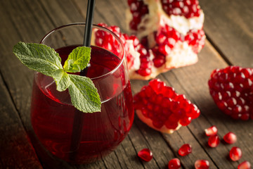 Pomegranate juice with fresh pomegranate fruits on wooden background. soft drink with lime, mint and ice.