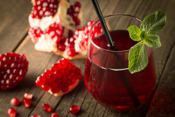 Pomegranate juice with fresh pomegranate fruits on wooden background. soft drink with lime, mint...