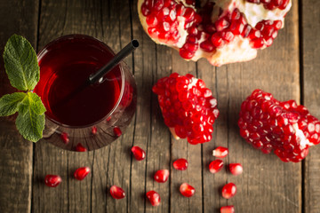 Pomegranate juice with fresh pomegranate fruits on wooden background. soft drink with lime, mint and ice.