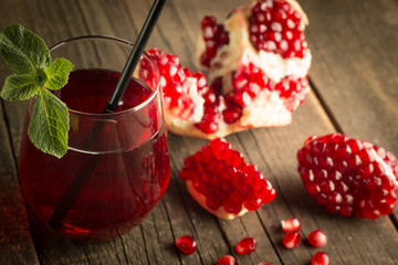Pomegranate juice with fresh pomegranate fruits on wooden background. soft drink with lime, mint and ice.