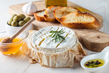 Camembert and brie cheese on wooden background with tomatoes, letuce and garlic. Italian food. Dairy products.