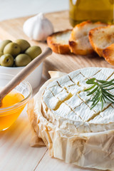 Camembert and brie cheese on wooden background with tomatoes, letuce and garlic. Italian food. Dairy products.