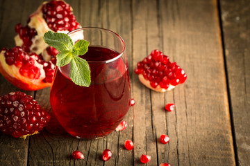 Pomegranate juice with fresh pomegranate fruits on wooden background. soft drink with lime, mint and ice.