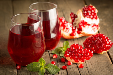 Pomegranate juice with fresh pomegranate fruits on wooden background. soft drink with lime, mint and ice.