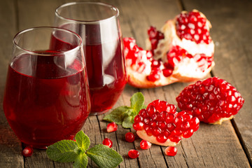 Pomegranate juice with fresh pomegranate fruits on wooden background. soft drink with lime, mint and ice.