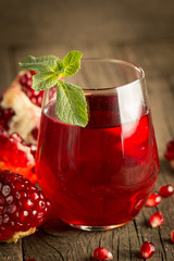 Pomegranate juice with fresh pomegranate fruits on wooden background. soft drink with lime, mint and ice.