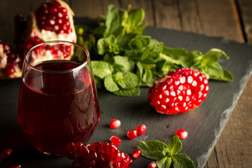 Pomegranate juice with fresh pomegranate fruits on wooden background. soft drink with lime, mint and ice.
