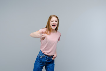 Young attractive girl showing thumbs up isolated over gray background