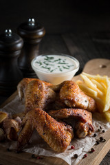 Barbecue grilled chicken wings close up with fries, tomato ketchup sauce and beer on wooden background. Meat food concept. 