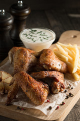 Barbecue grilled chicken wings close up with fries, tomato ketchup sauce and beer on wooden background. Meat food concept. 